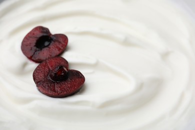 Tasty yogurt with cut cherry as background, closeup. Space for text