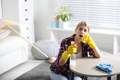 Photo of Lazy young woman wiping table at home. Cleaning and housework