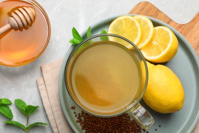 Photo of Buckwheat tea, lemon and honey on light grey marble table, flat lay