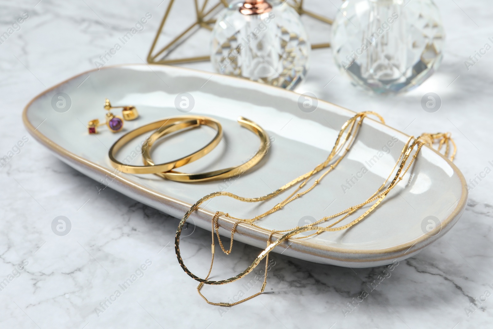 Photo of Different elegant bijouterie on white marble table, closeup