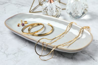 Different elegant bijouterie on white marble table, closeup