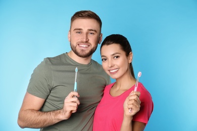 Photo of Young couple with toothbrushes on color background. Teeth care