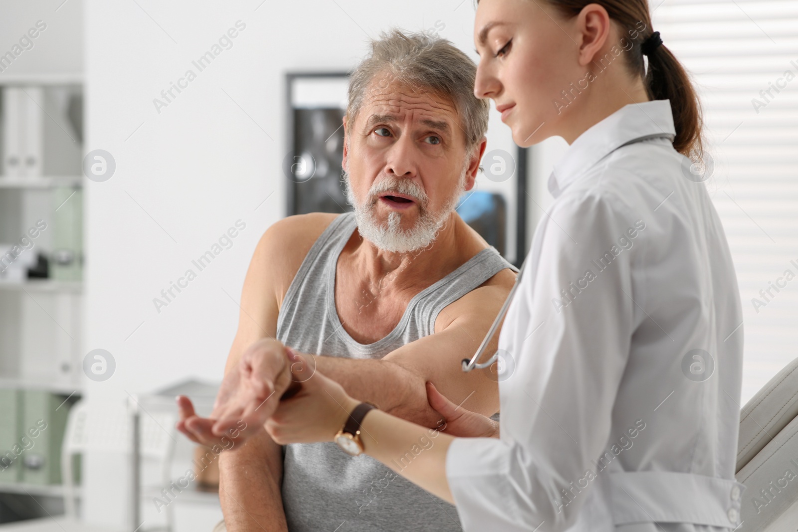 Photo of Orthopedist examining patient with injured arm in clinic