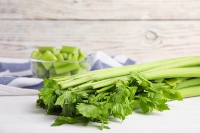 Fresh ripe green celery on white wooden table, closeup. Space for text