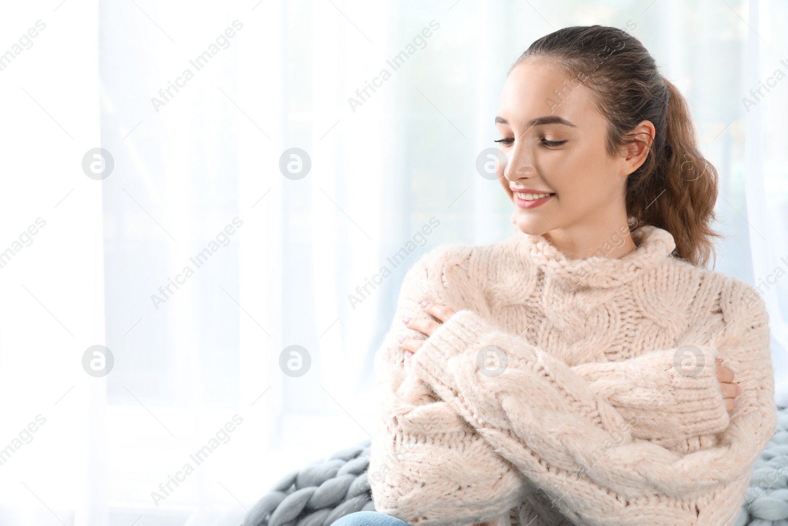 Photo of Portrait of beautiful teenage girl in warm cozy sweater on light background. Space for text