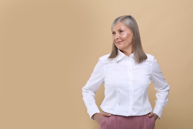 Portrait of beautiful senior woman on beige background. Space for text