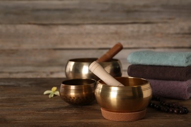 Composition with golden singing bowls on wooden table, space for text