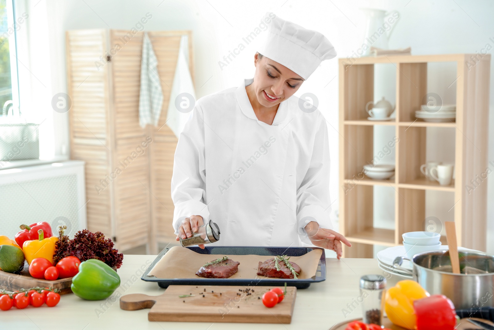 Photo of Professional female chef preparing meat on table in kitchen