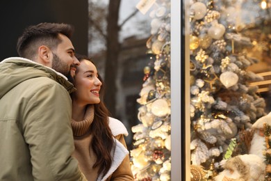 Photo of Lovely couple near store decorated for Christmas outdoors