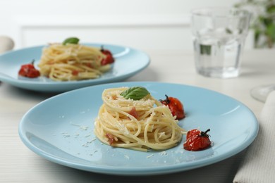 Photo of Tasty spaghetti with tomatoes and cheese served on white wooden table, closeup. Exquisite presentation of pasta dish