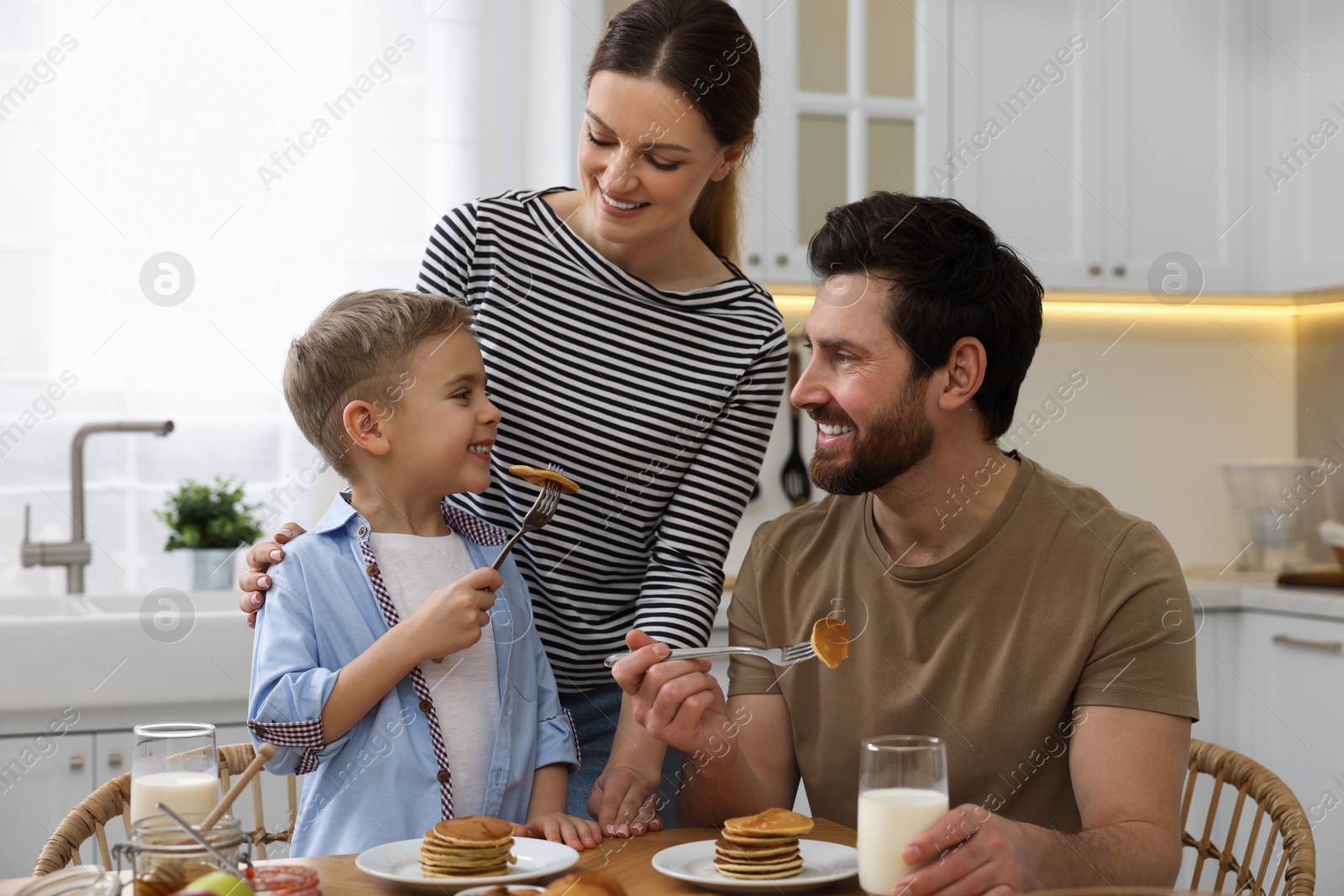 Photo of Happy family having breakfast at table in kitchen