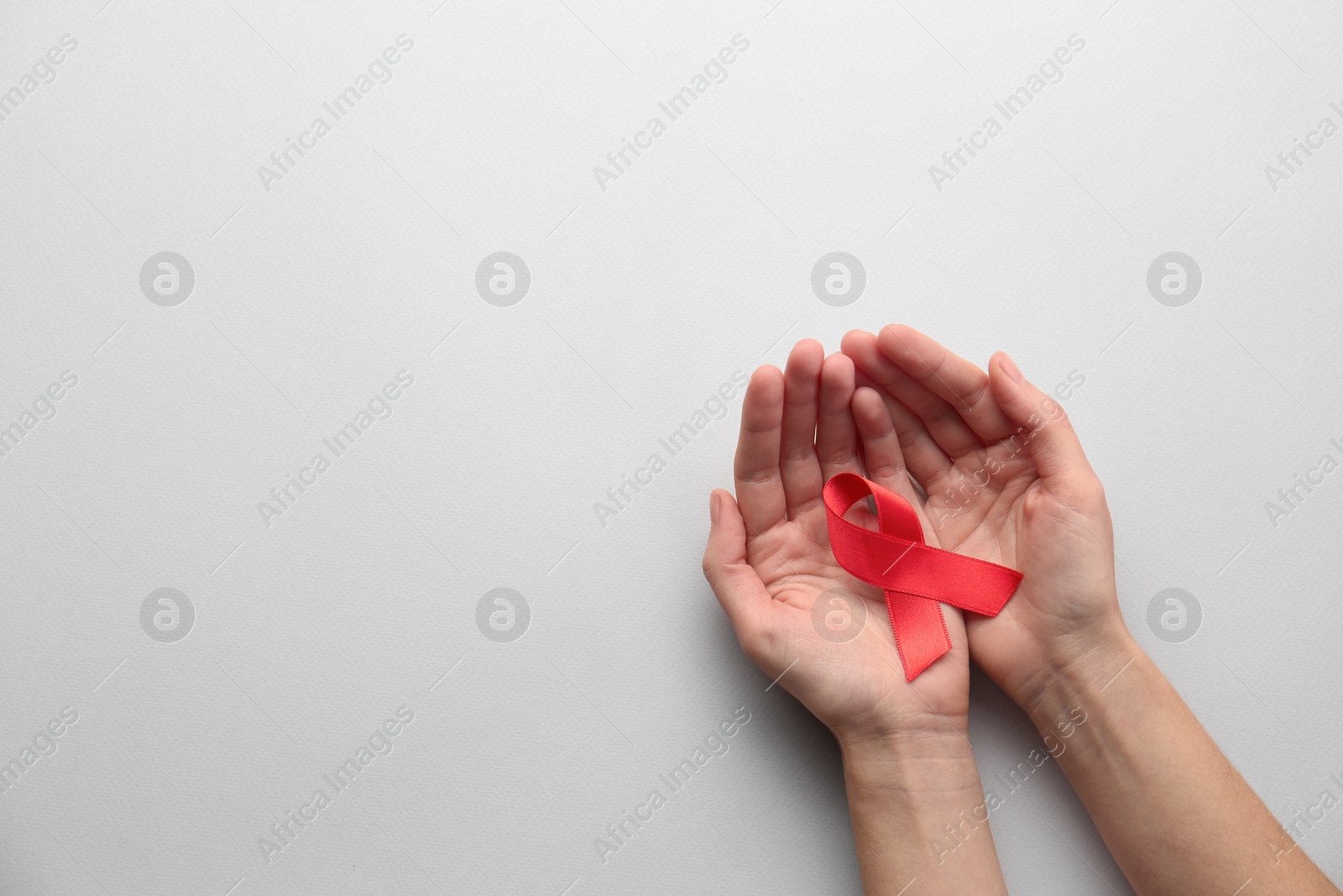 Photo of Woman holding red awareness ribbon on white background, top view with space for text. World AIDS disease day