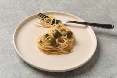 Photo of Heart made of tasty spaghetti, olives, cheese and fork on light grey table