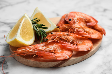 Delicious cooked shrimps with rosemary and lemon on white marble table