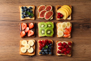 Tasty toasts with different spreads and fruits on wooden table, flat lay