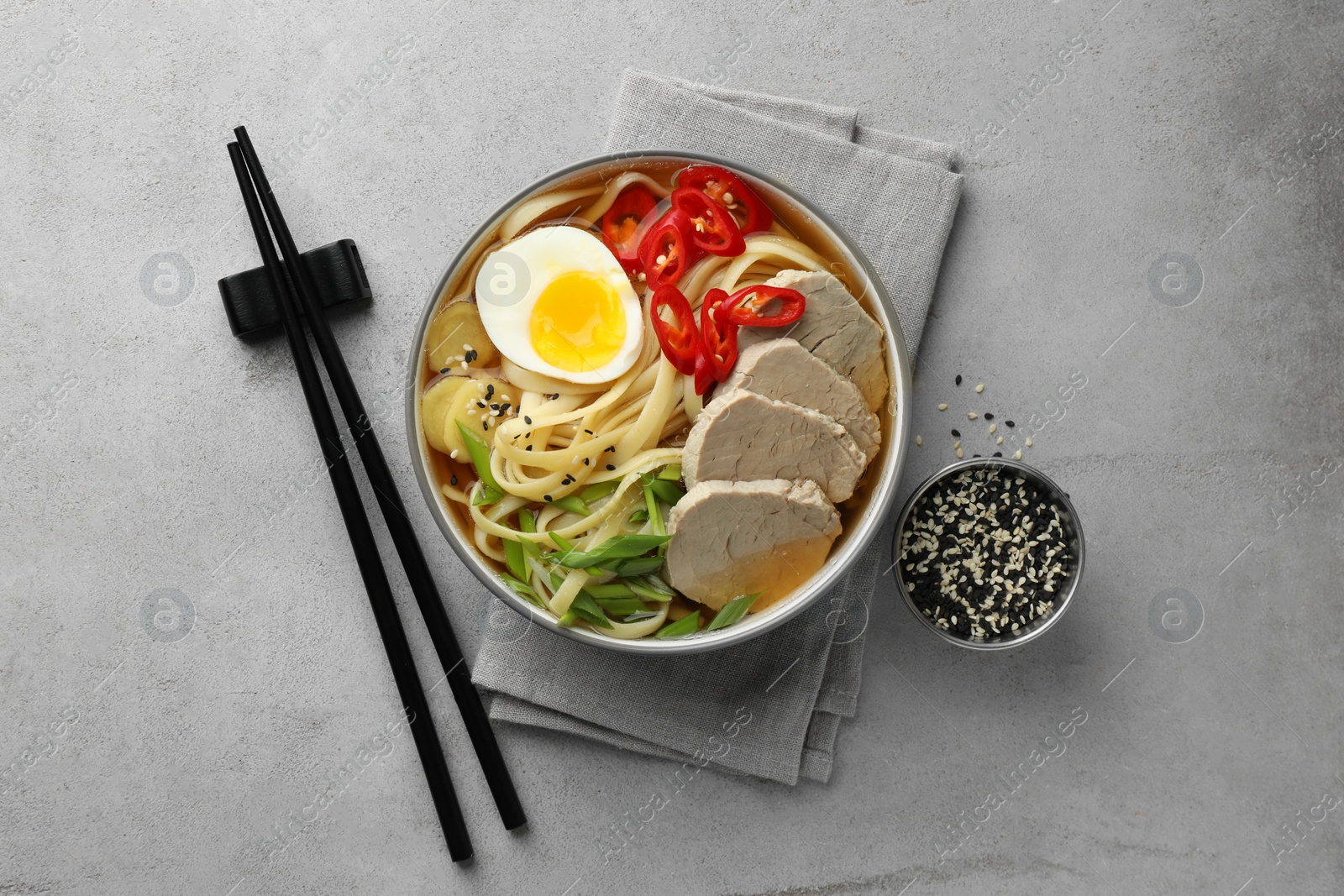 Photo of Delicious ramen in bowl served on light textured table, flat lay. Noodle soup