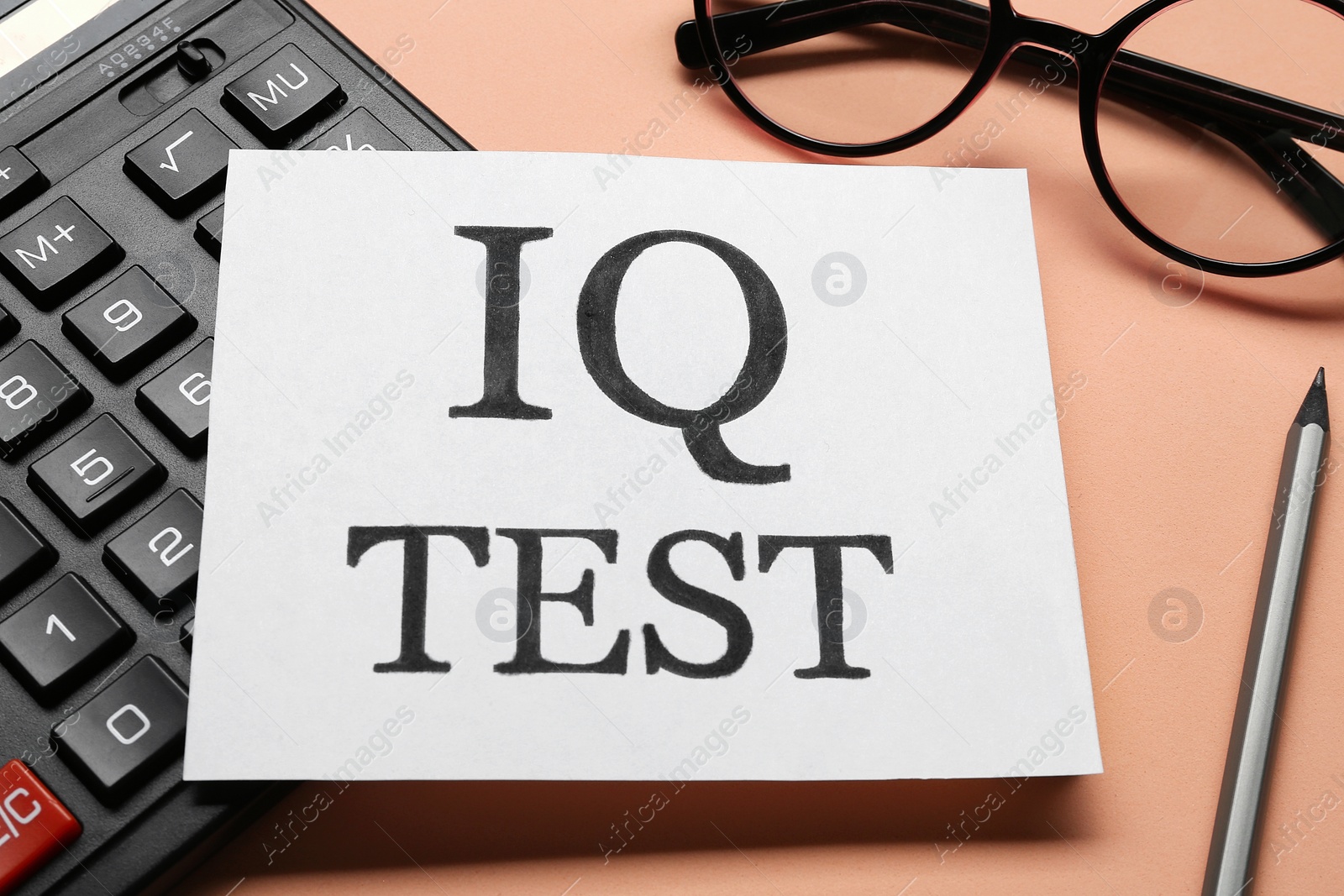 Photo of Note with text IQ Test, calculator, glasses and pencil on coral background, closeup