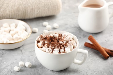 Photo of Cup of aromatic hot chocolate with marshmallows, cocoa powder on gray table, closeup