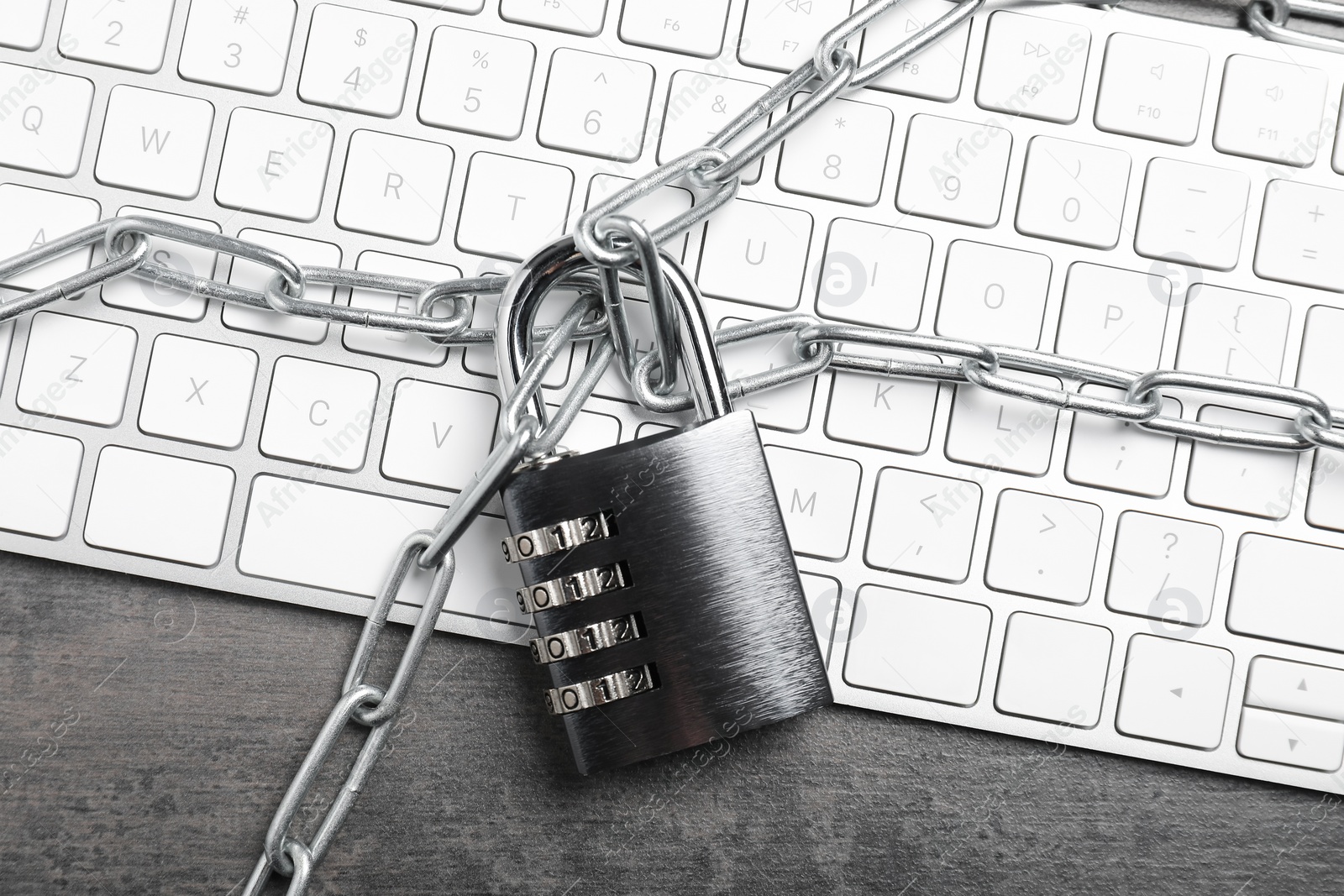 Photo of Cyber security. Metal combination padlock with chain and keyboard on grey table, top view