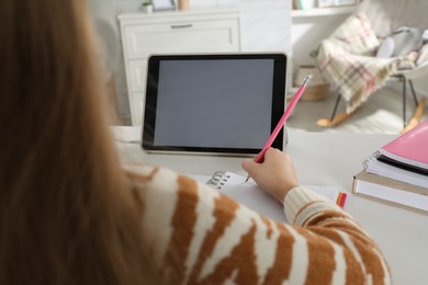 Cute little girl with modern tablet studying online at home, closeup. E-learning