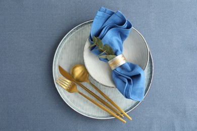 Stylish setting with cutlery, dishes, napkin and floral decor on table, top view