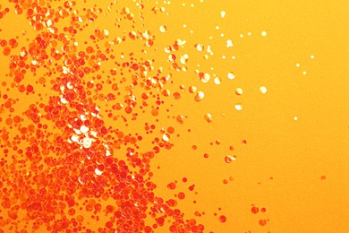 Shiny bright glitter on orange background, flat lay. Space for text