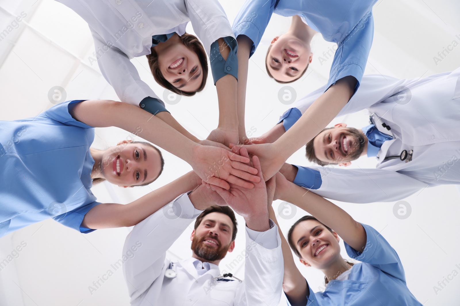 Photo of Team of medical doctors putting hands together indoors, bottom view