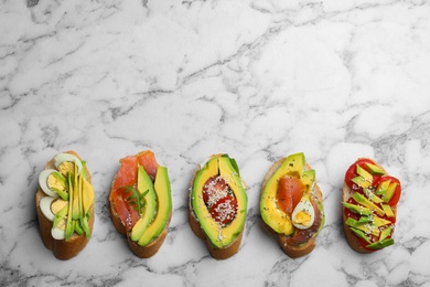 Delicious avocado sandwiches on white marble table, flat lay. Space for text