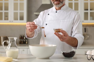 Photo of Professional chef making dough at white marble table indoors, closeup