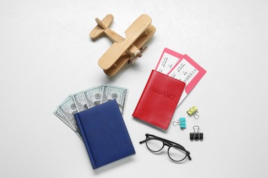 Photo of Flat lay composition with tickets, passport and dollars on white table. Business trip