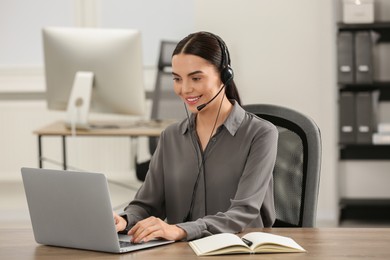 Photo of Hotline operator with headset working on laptop in office