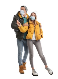 Couple in face masks and warm clothes on white background. Winter travel