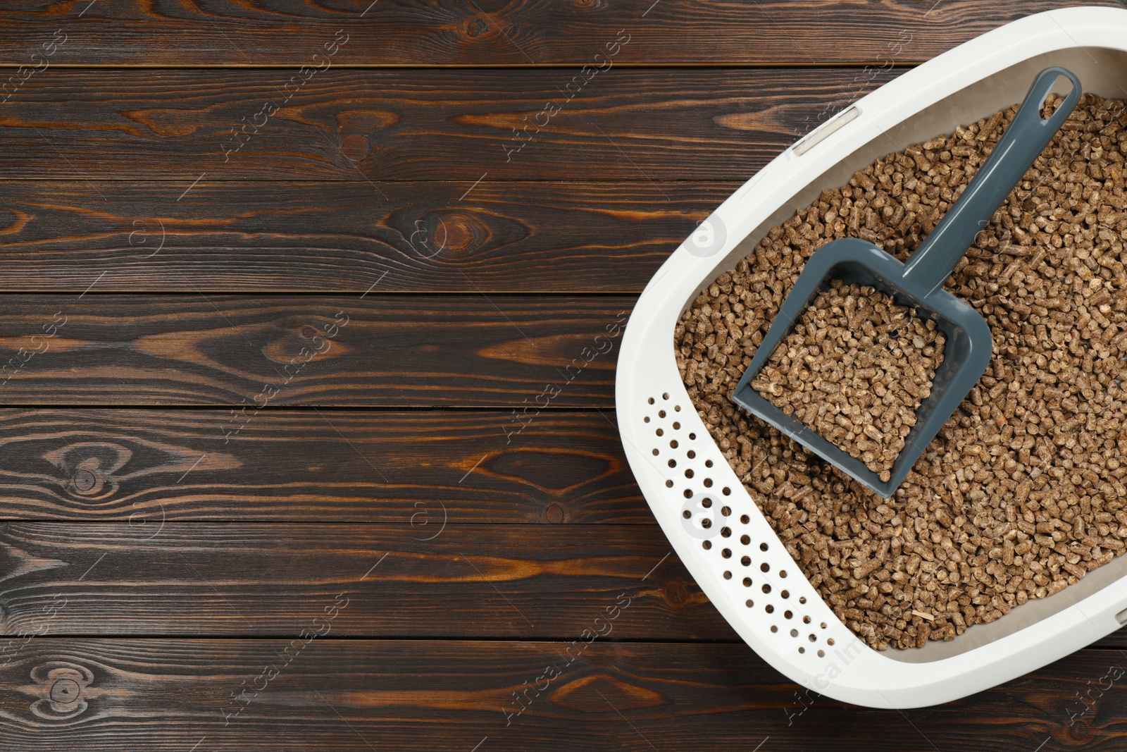 Photo of Cat litter tray with filler and scoop on wooden background, top view. Space for text