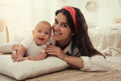 Photo of Happy young mother with her cute baby on floor at home