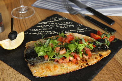 Photo of Delicious grilled fish served on wooden table