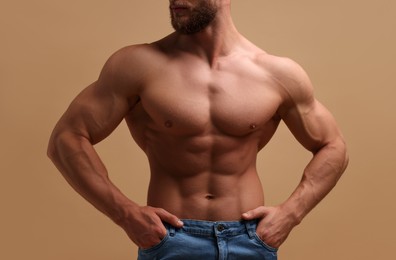 Photo of Muscular man showing abs on beige background, closeup. Sexy body