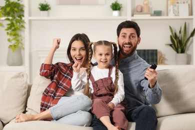 Happy family watching TV on sofa at home