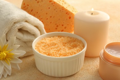 Composition with bowl of orange sea salt on beige table, closeup