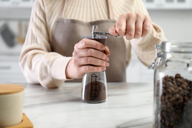 Photo of Woman using coffee grinder at table indoors, closeup