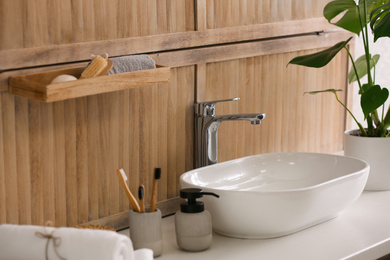 Stylish vessel sink near wooden wall in modern bathroom