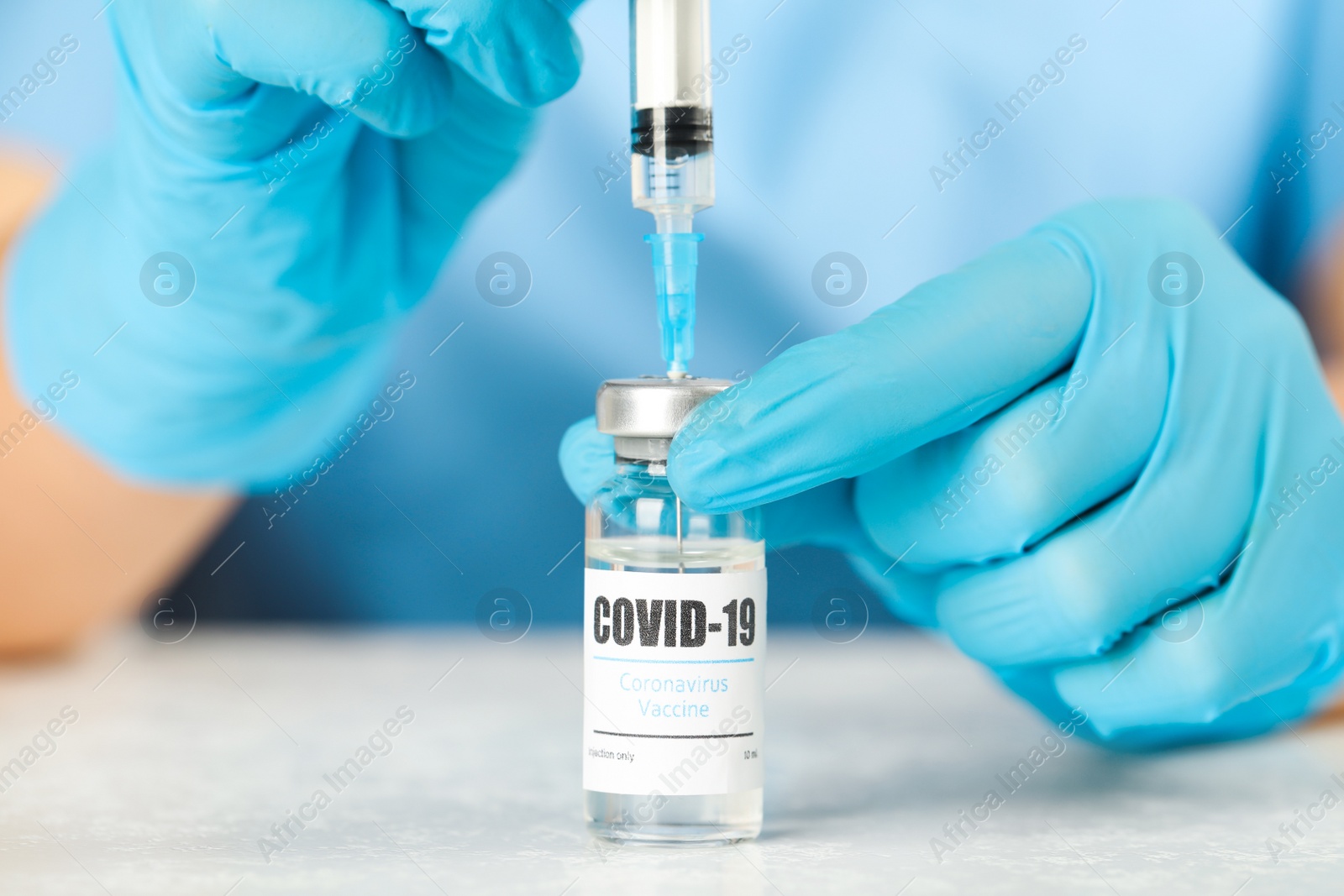 Photo of Doctor filling syringe with coronavirus vaccine at table in laboratory, closeup