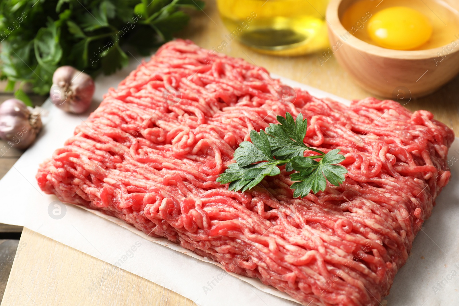 Photo of Raw ground meat and parsley on table, closeup