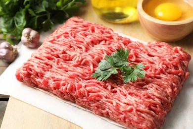 Photo of Raw ground meat and parsley on table, closeup