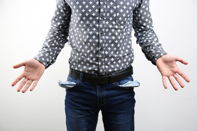 Photo of Man showing empty pockets on light background, closeup