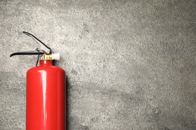 Photo of One red fire extinguisher on gray textured background, top view. Space for text