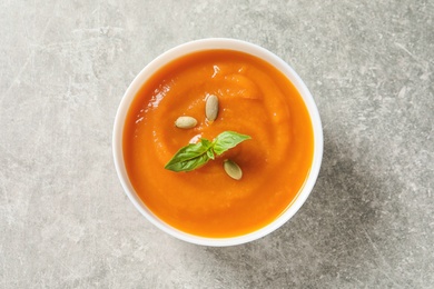 Photo of Bowl of tasty sweet potato soup on grey background, top view