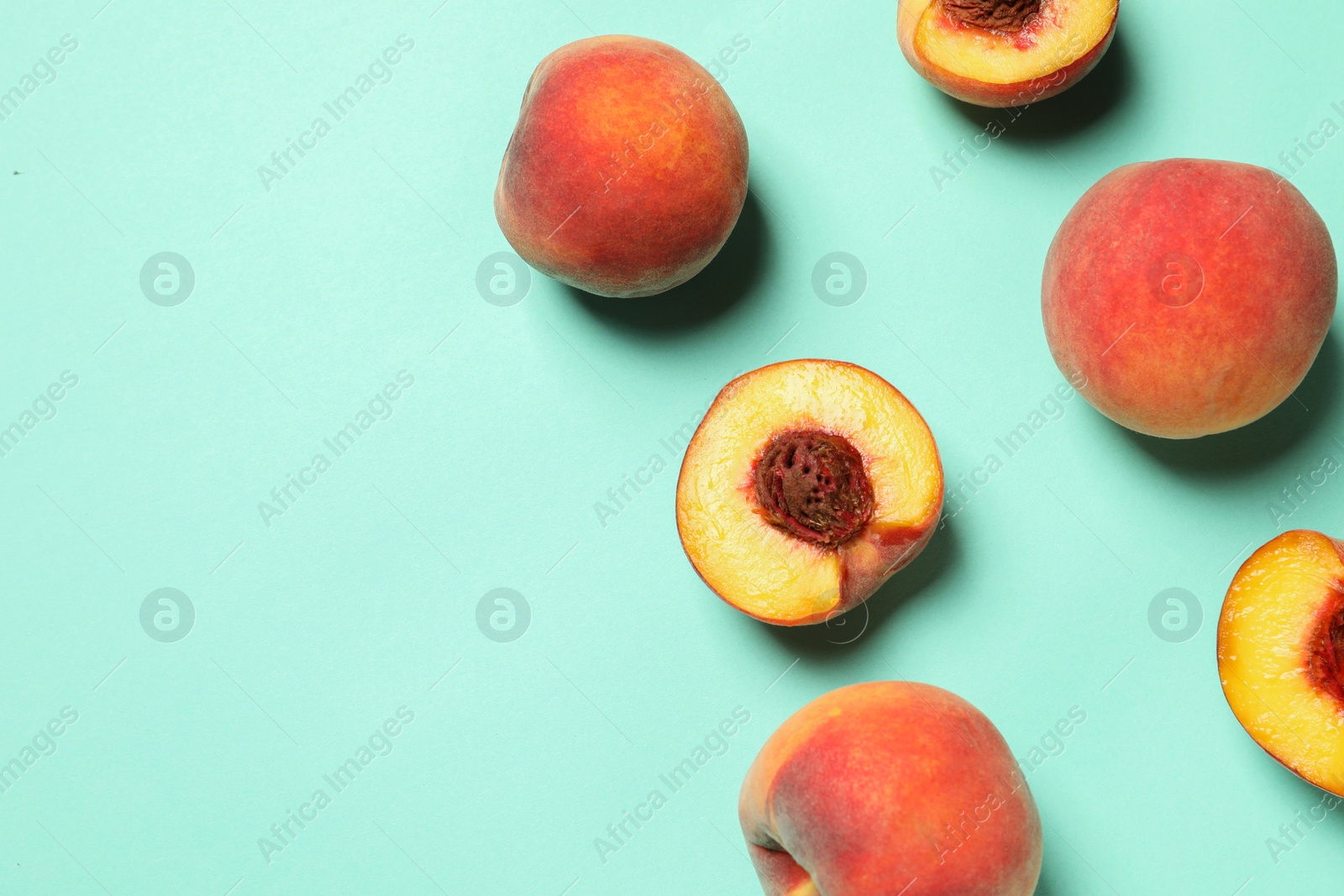 Photo of Cut and whole fresh ripe peaches on light blue background, flat lay. Space for text