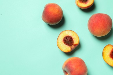 Cut and whole fresh ripe peaches on light blue background, flat lay. Space for text