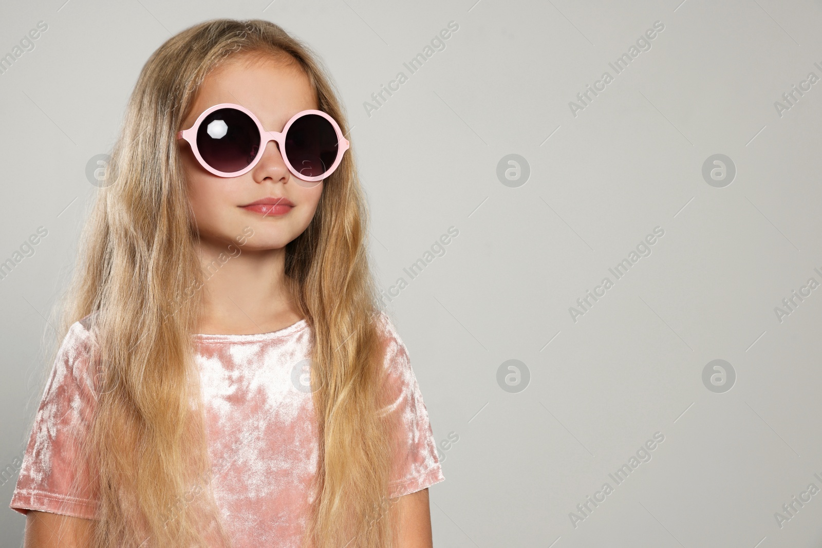 Photo of Girl in stylish sunglasses on light grey background, space for text