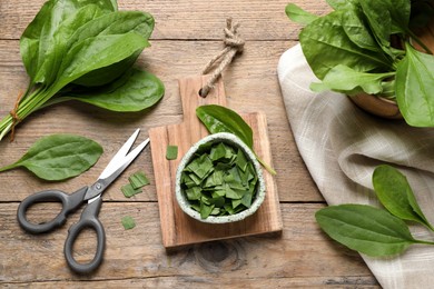 Photo of Broadleaf plantain leaves and scissors on wooden table, flat lay